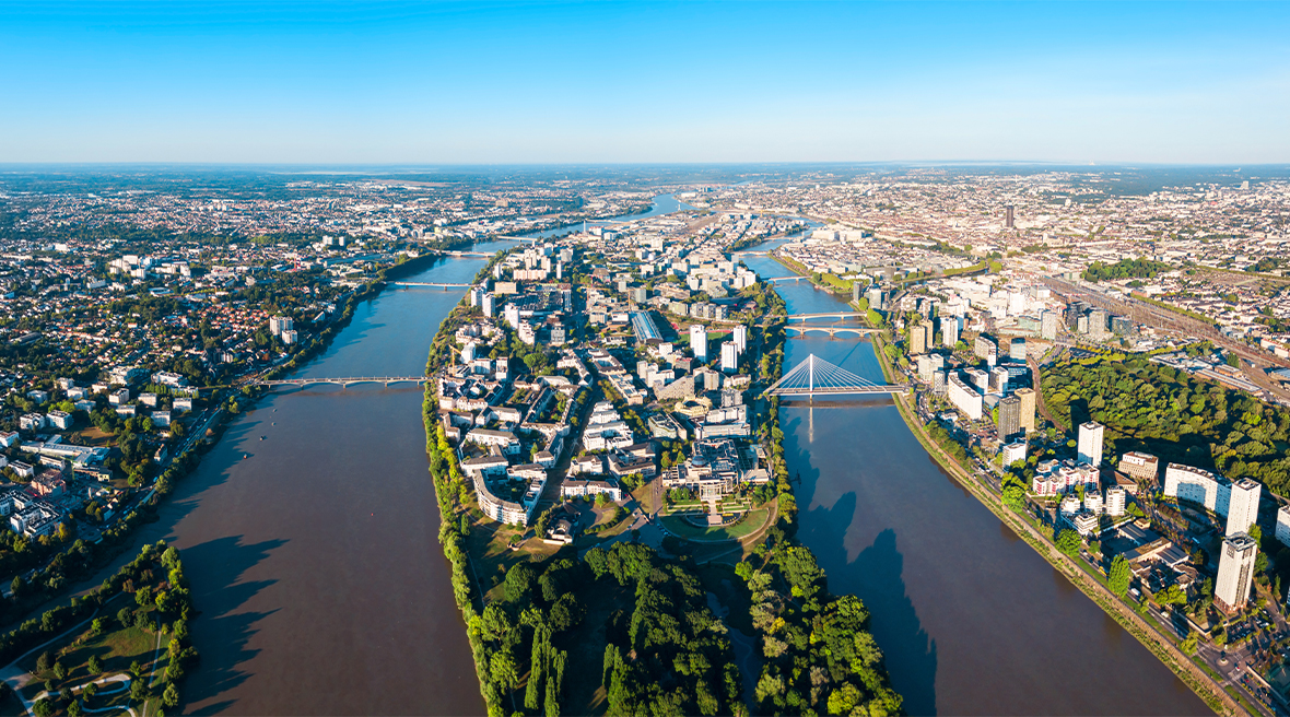 aerial view of a city split over the banks of two rivers running towards a blue horizon